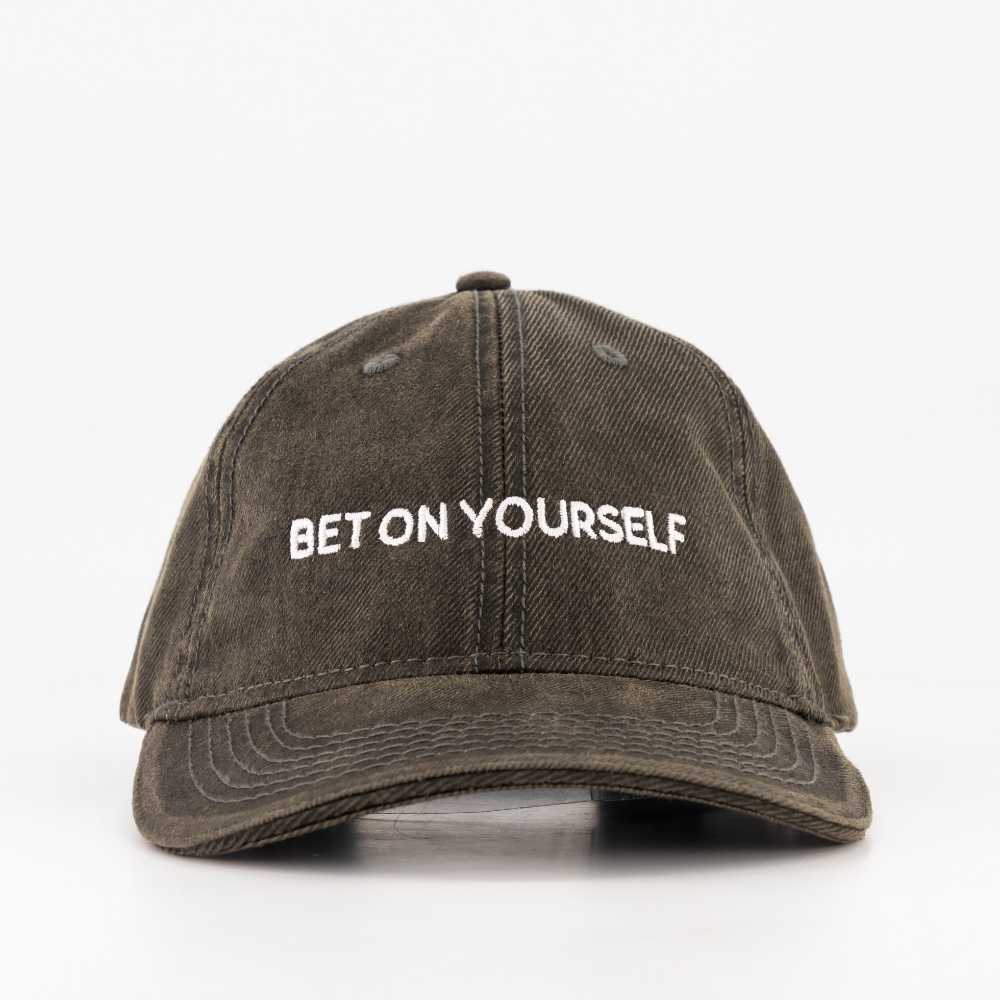 A washed black baseball cap with the text 'BET ON YOURSELF' printed in white on the front. From the brand BIGTYNSONLY.